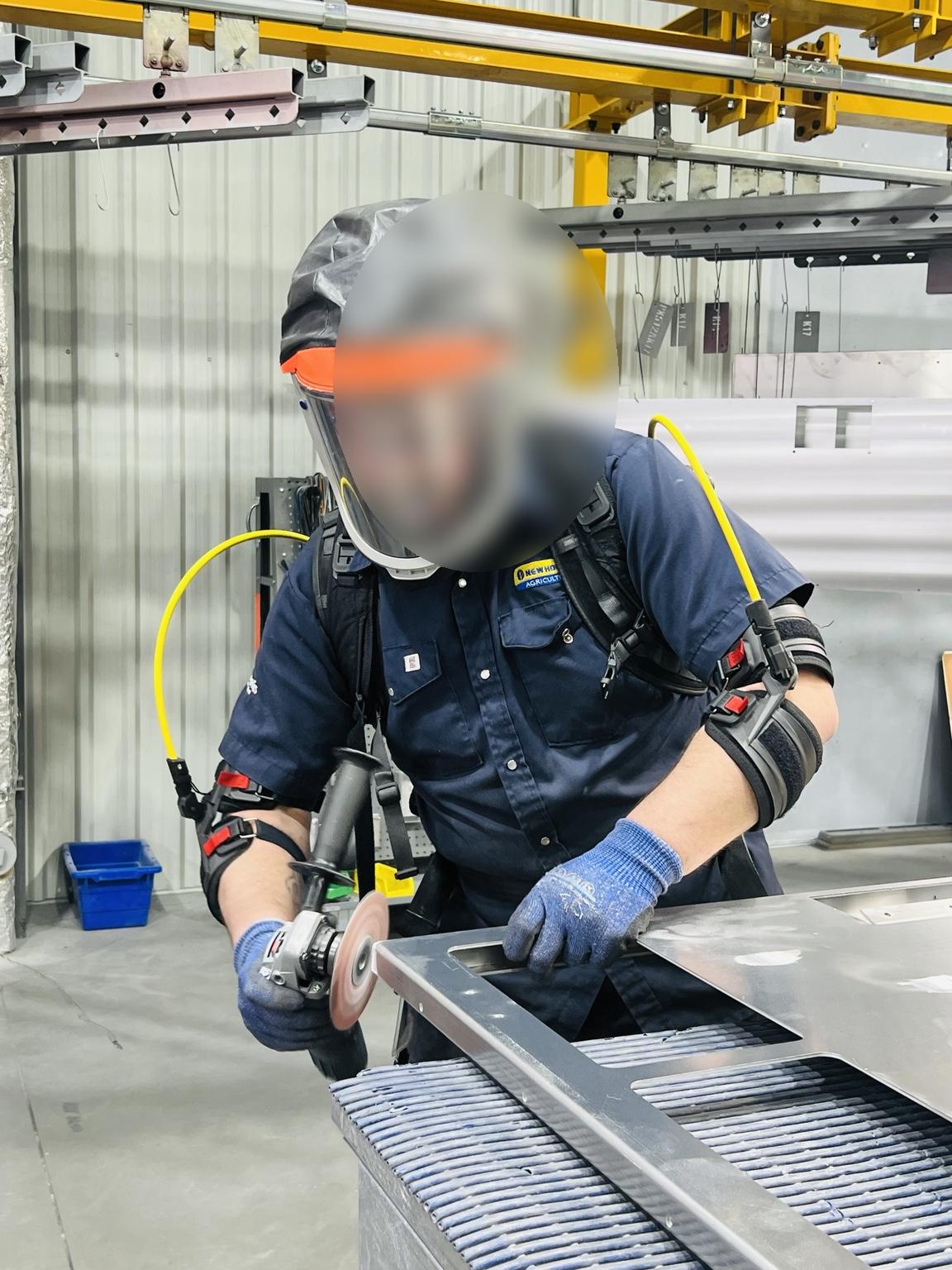 Operator grinding steel while wearing a Hapo Front exoskeleton to support and relieve the shoulders